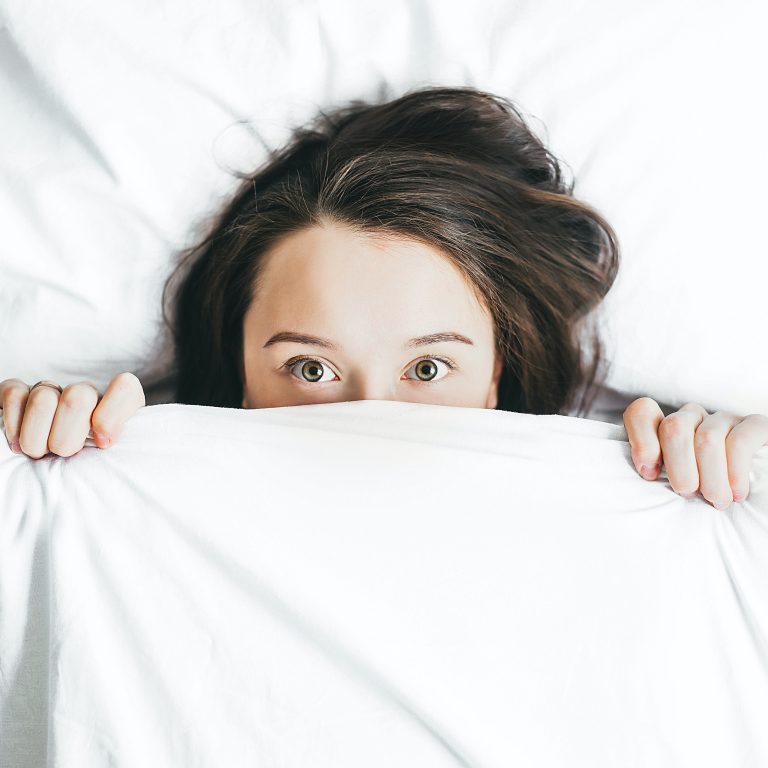 Woman in bed worried about signs of bedbugs